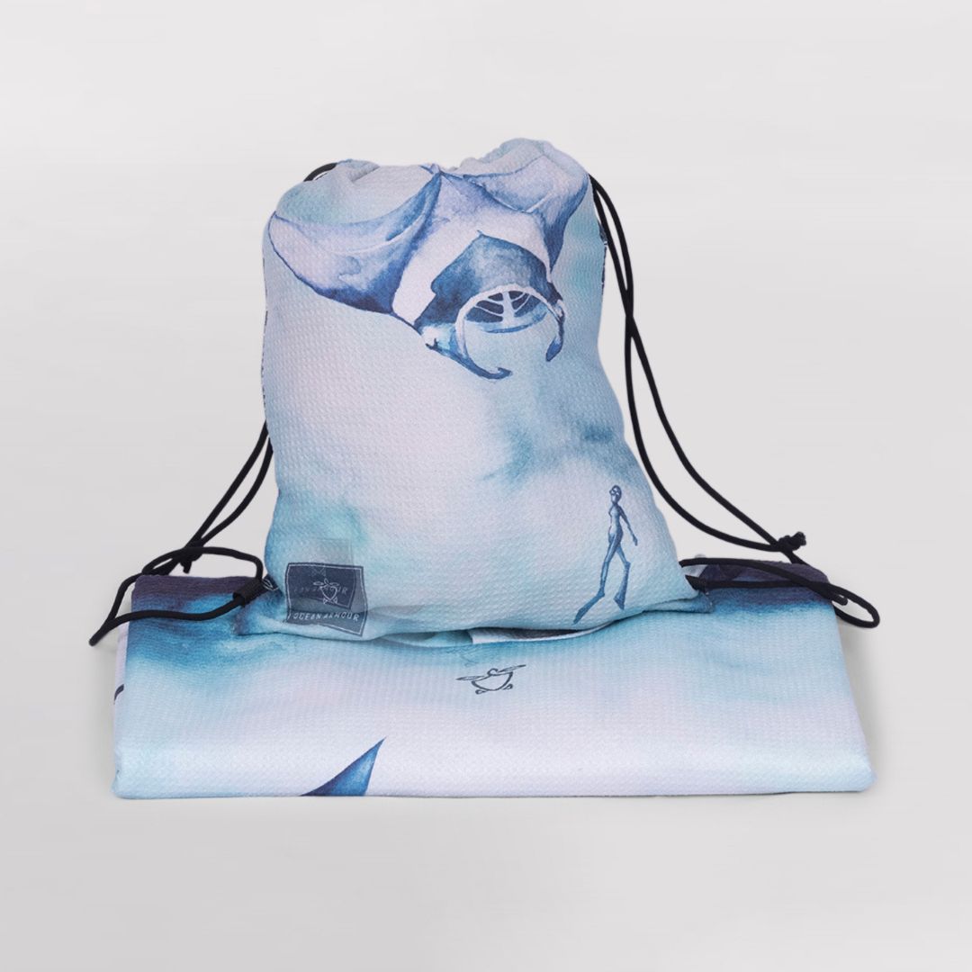 A drawstring gym bag with a light blue and white ocean-themed print, shown with a matching folded towel or blanket underneath on a light gray background.