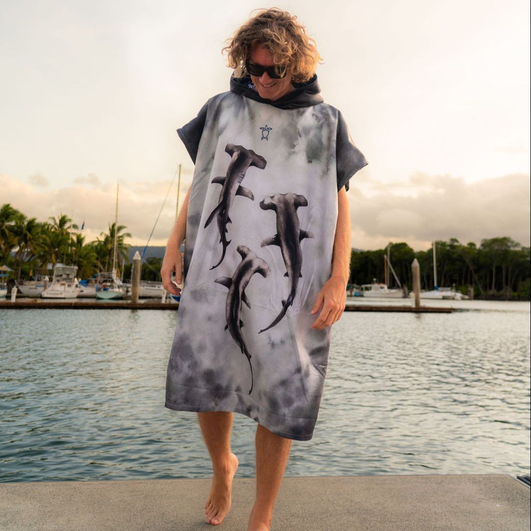 Adult wearing a hooded Hammerhead Shark Changing Poncho Towel featuring three hammerhead shark illustrations on the front.