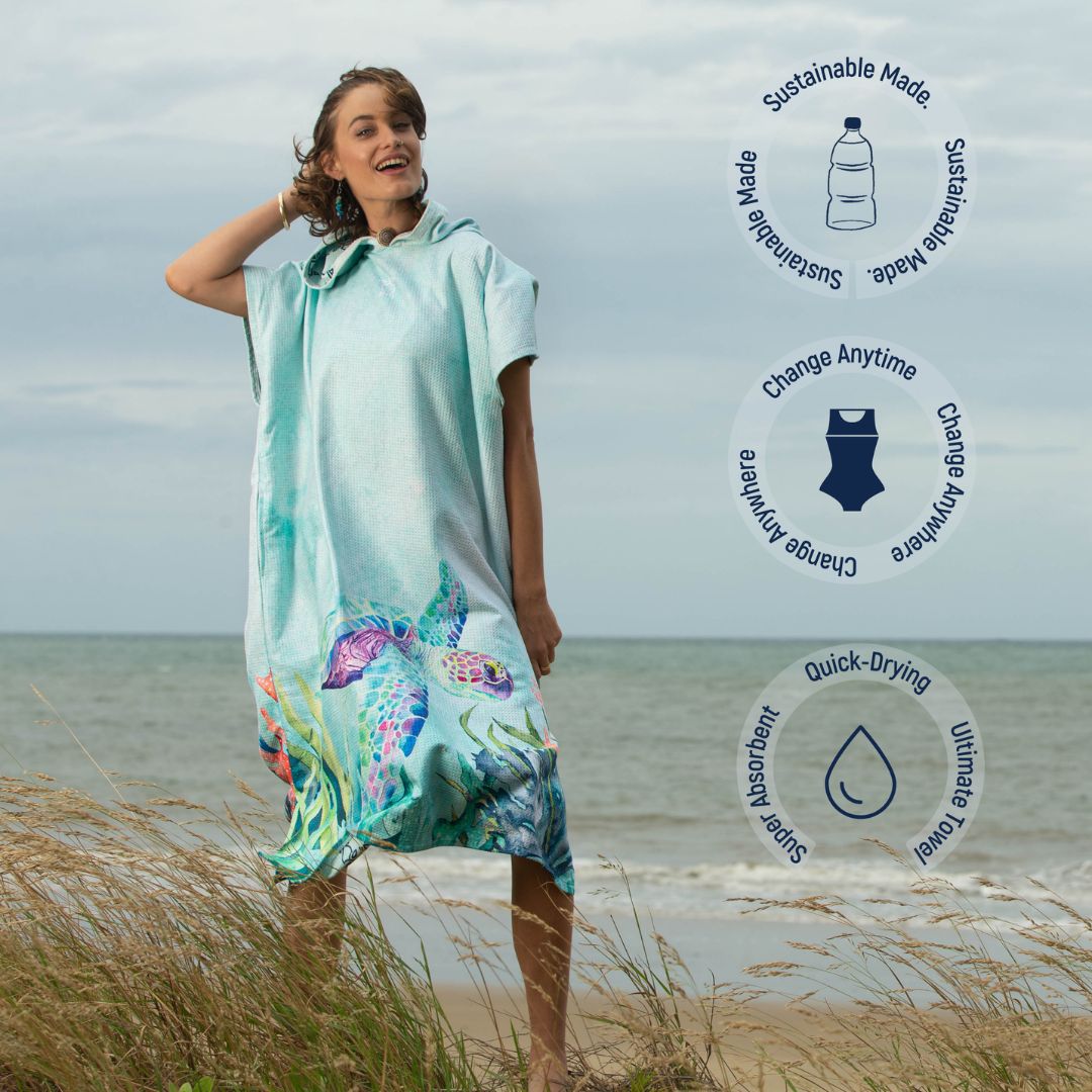 A woman stands on a beach wearing a hooded towel poncho with a colorful sea turtle print. Three circular feature callouts appear on the right, highlighting sustainable material, anytime changing, quick-drying, and touch-friendly properties.