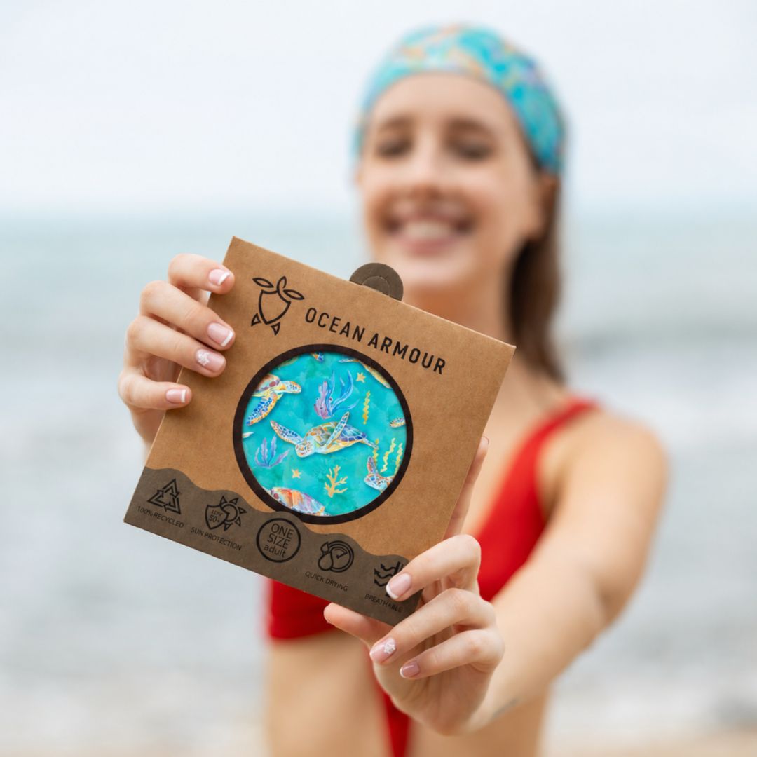 Person holding a 'Ocean Armour' product packaging with a blurred beach background