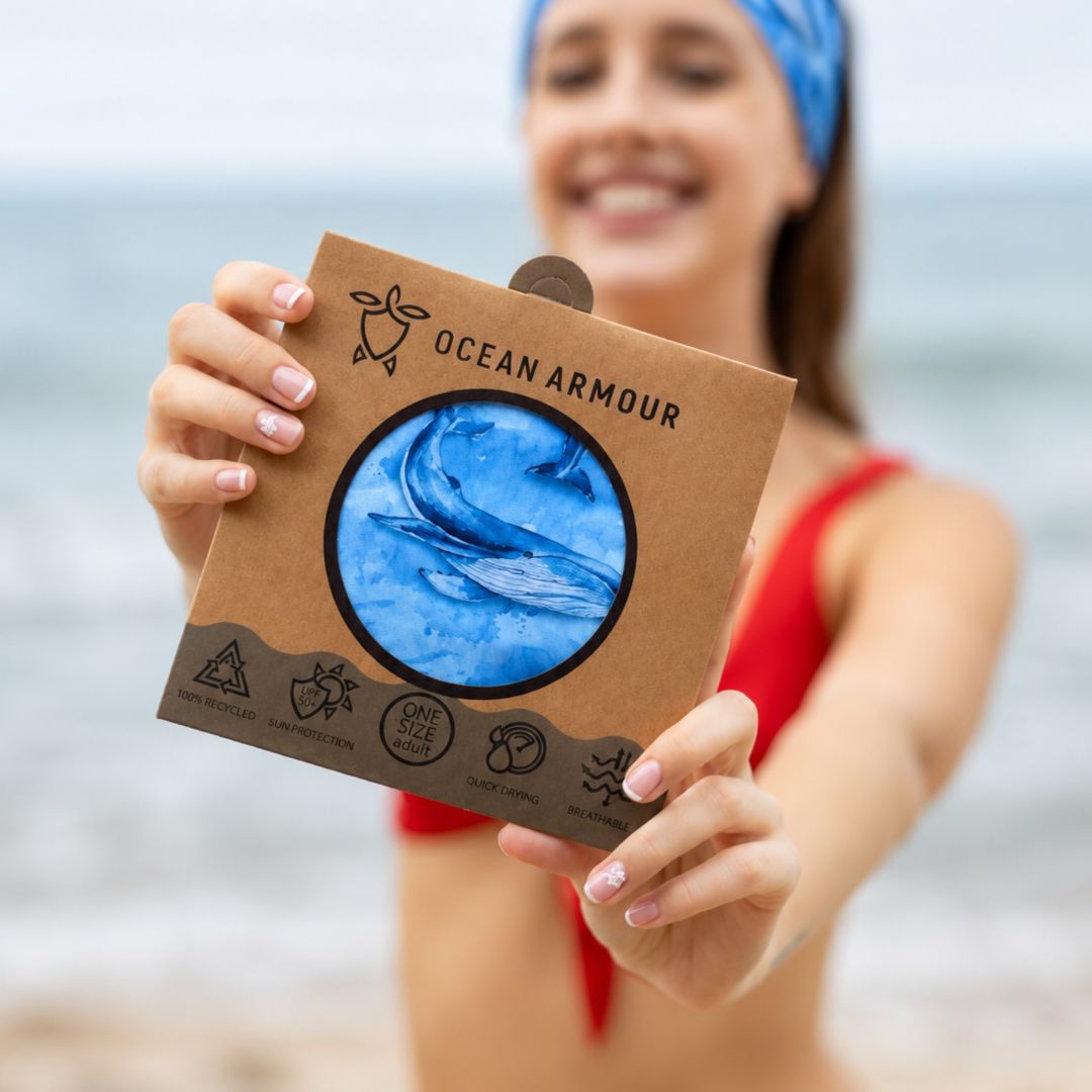 Person holding an 'Ocean Armour' product packaging on a beach