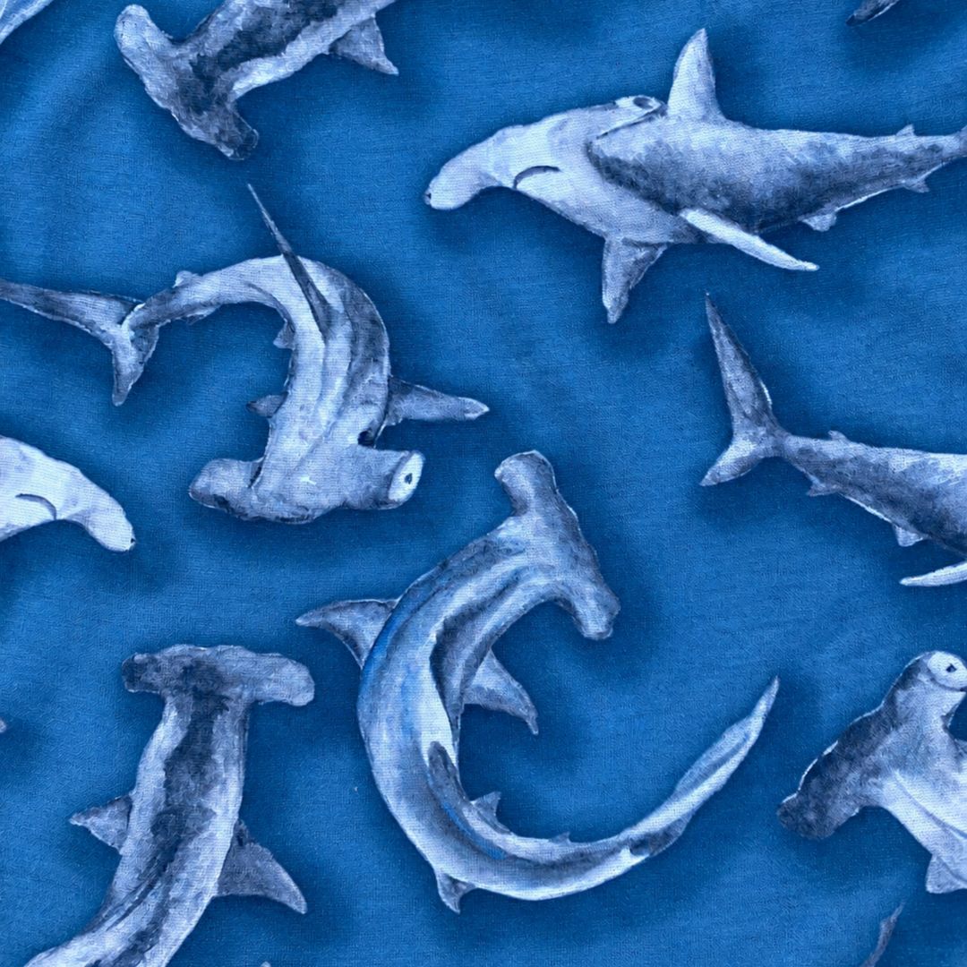 Blue fabric featuring a repeating pattern of hammerhead sharks in shades of gray and white.