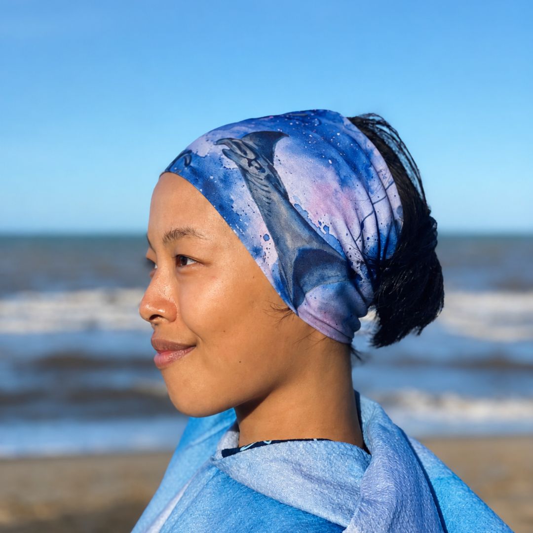 Person wearing a blue patterned headscarf on a beach