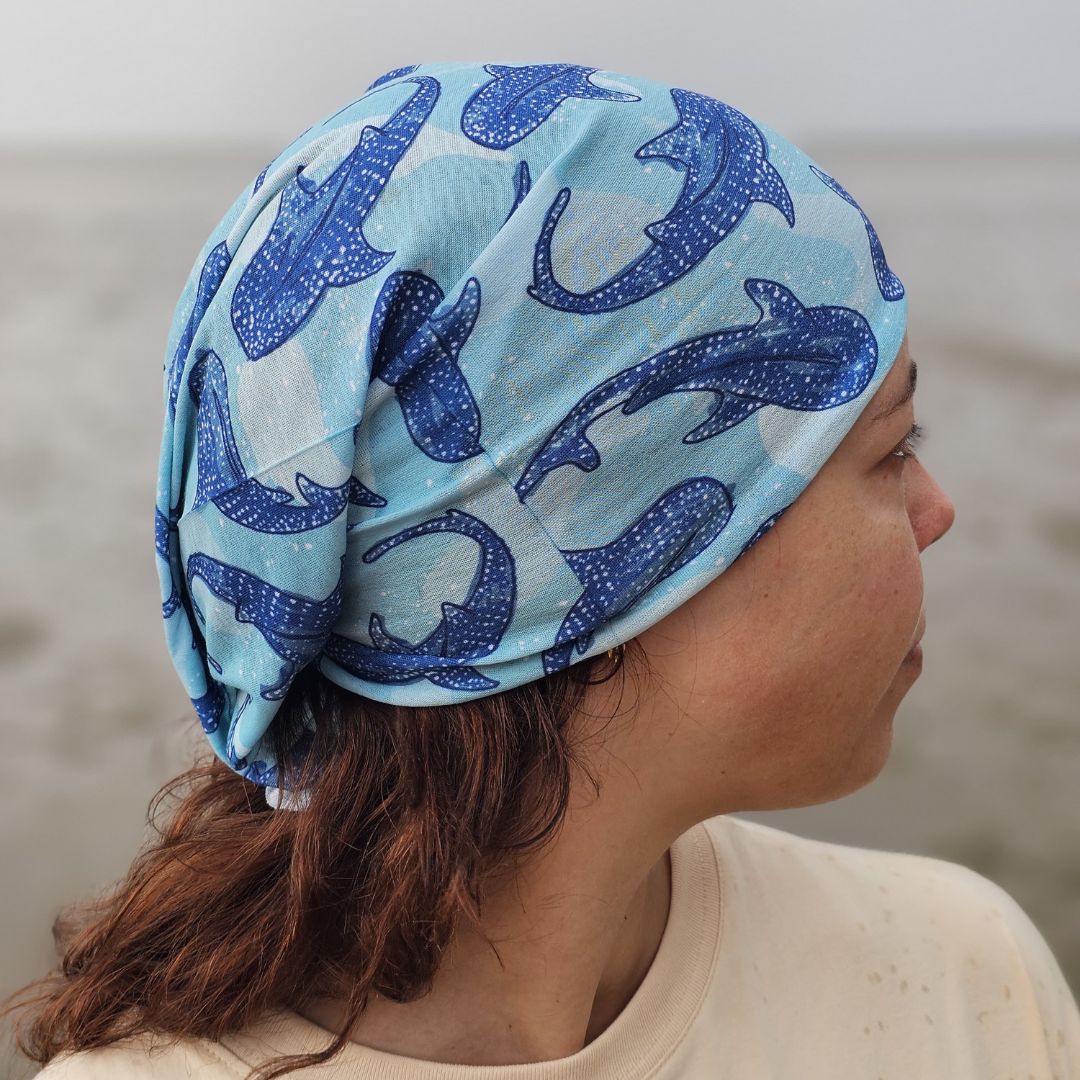 Lifestyle image of the Whale Shark Neck Gaiter worn as a headband, featuring a blue whale shark print on a light blue fabric.